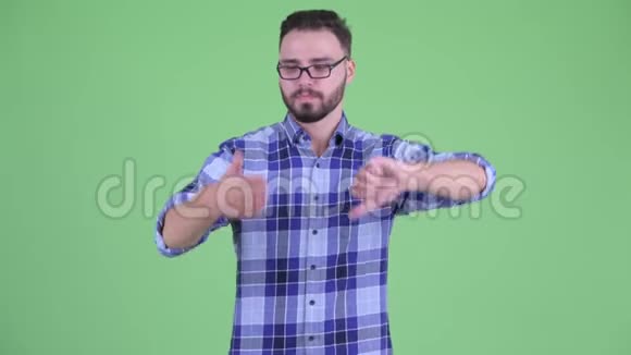 困惑的年轻留着胡子的时髦男人在竖起大拇指和竖起大拇指之间做出选择视频的预览图