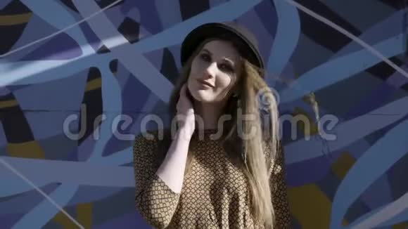 年轻漂亮的时尚女人的肖像戴着黑色帽子摆在蓝色的灰色背景上行动模特穿着视频的预览图