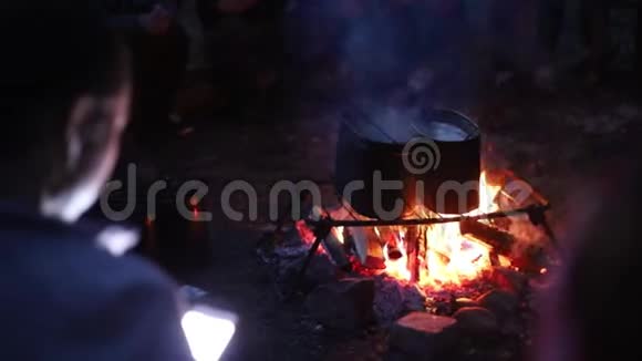 人们晚上用篝火在水桶里烧水视频的预览图