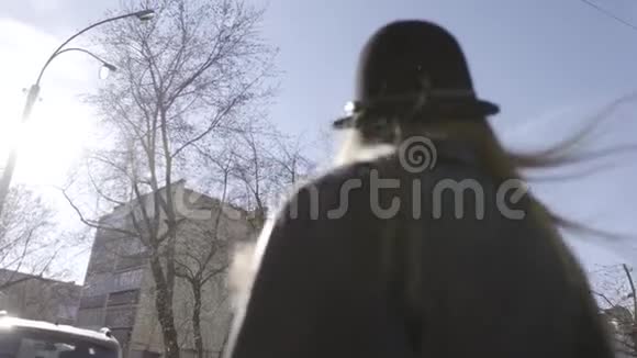 后景一位年轻漂亮的模特女孩戴着宽边帽子和黑色皮夹克在城里散步行动视频的预览图