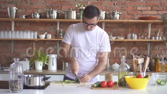 戴眼镜的年轻人在厨房里切蔬菜感到心痛视频的预览图