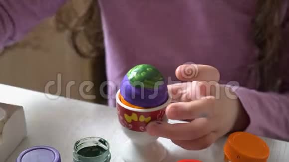 一个小女孩在桌旁的家里画了一个色彩鲜艳的复活节彩蛋快关门4K25fps视频的预览图