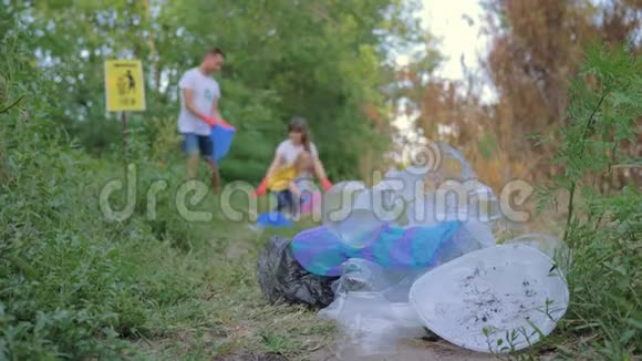 环境污染女人和男人带着孩子女孩在清洁自然时把垃圾收集到垃圾袋中没有集中注意力视频的预览图