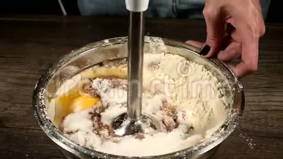厨房里的一个糕点女孩在一个金属碗里用搅拌机打着面团做海绵蛋糕面粉鸡蛋和视频的预览图
