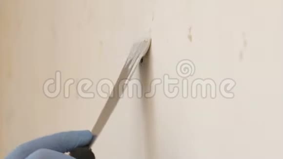 蓝手套带腻子刀的修理工正在墙上的一个洞上涂贴修的现代技术自然光线视频的预览图