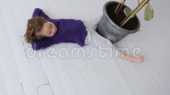 穿灰色裤子的小女孩正躺在白色地板上视频的预览图