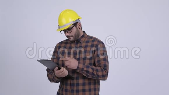 一位留胡子的印度建筑工人在剪贴板上看书视频的预览图