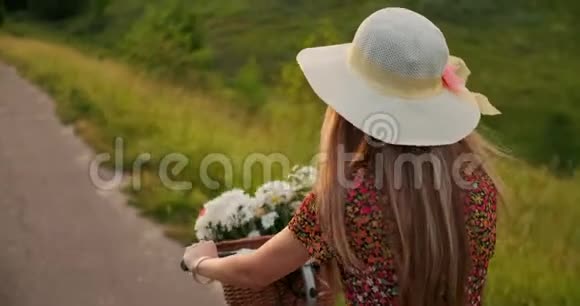 快乐的女孩带着一束花骑着一辆自行车戴着帽子穿着一件夏天的短裙视频的预览图