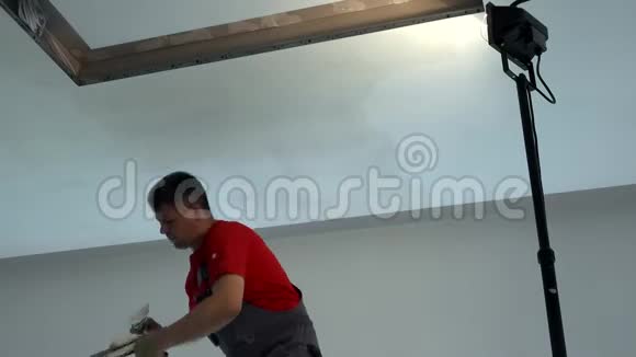 抹刀工人在石膏板天花板上涂上填料照明场所视频的预览图