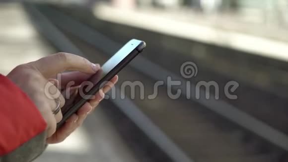 年轻女子站在站台上用智能手机等候火车视频的预览图