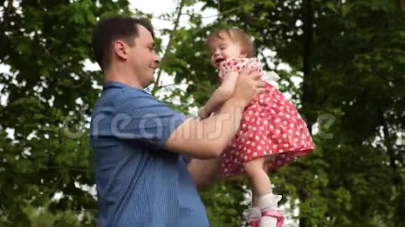 快乐的爸爸把他的女儿放在绿色公园里和她一起散步视频的预览图