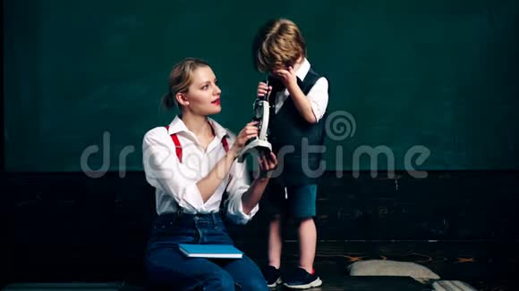 一个带着小男孩的女人看着绿色瞳孔s板背景上的显微镜课堂教师视频的预览图