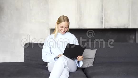 女人早上在房间的沙发上用笔记本电脑工作视频的预览图