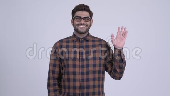快乐的年轻留着胡子的印度时髦男人微笑着挥舞着手视频的预览图
