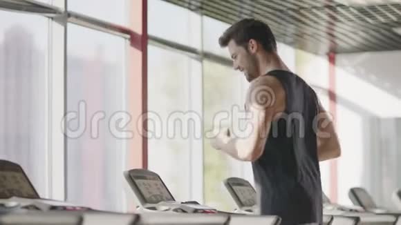 快乐的男人在跑步机上跑步在健身房训练视频的预览图