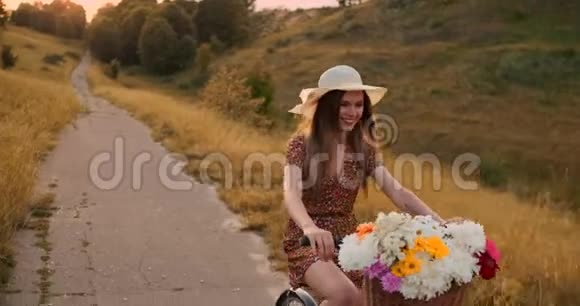 快乐的女孩带着一束花骑着一辆自行车戴着帽子穿着一件夏天的短裙视频的预览图