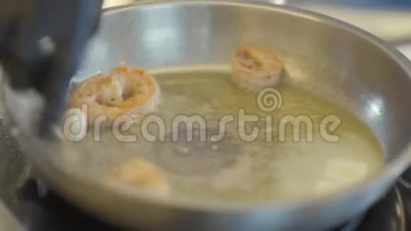用虾仁把煎锅合上用黄油和大蒜一起煎用黑手套搅拌大虾视频的预览图