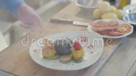 厨师的手推着盘子桌子上放着热气腾腾的蔬菜有玉米肉片的盘子视频的预览图