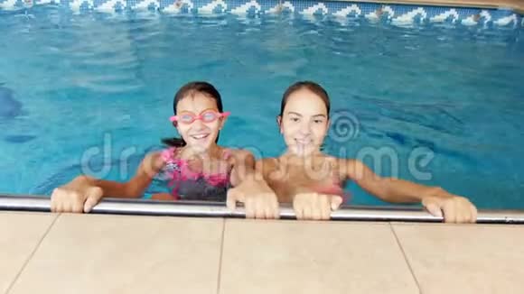 两个微笑的少女在镜头下观看并在游泳池潜水视频的预览图