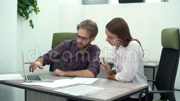 男人和女人在舒适的现代办公室工作桌上有笔记本电脑工作过程创意商业团队视频的预览图