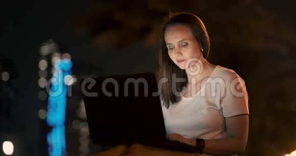 年轻的女设计师晚上在棕榈树下的笔记本电脑上远程工作视频的预览图