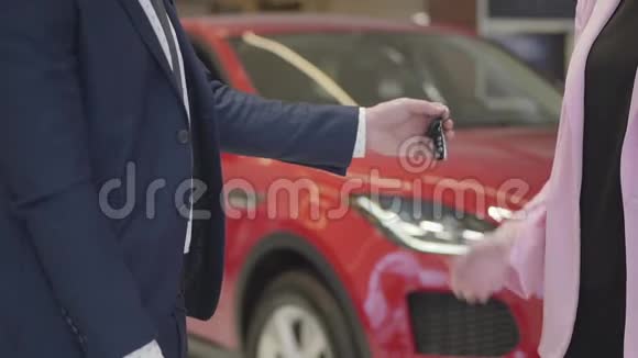 穿西装的男人把钥匙丢在女人的手里但他们却紧紧地落在地板上红色的汽车视频的预览图