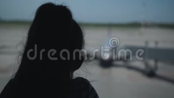 机场窗口一个孤独的小女孩的剪影视频的预览图