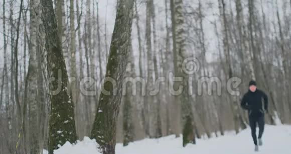 一个年轻人在冬天的森林里晨跑累了停下来喘口气他恢复了体力视频的预览图