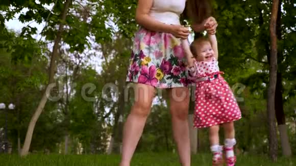 妈妈牵着女儿的手和她握手快乐的孩子笑了小女儿在绿茵上玩妈妈视频的预览图