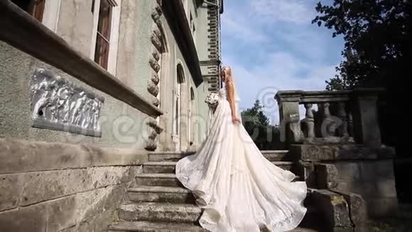 戴德乌斯比迪尔穿着优雅的婚纱站在楼梯上宫殿旁有一束鲜花视频的预览图