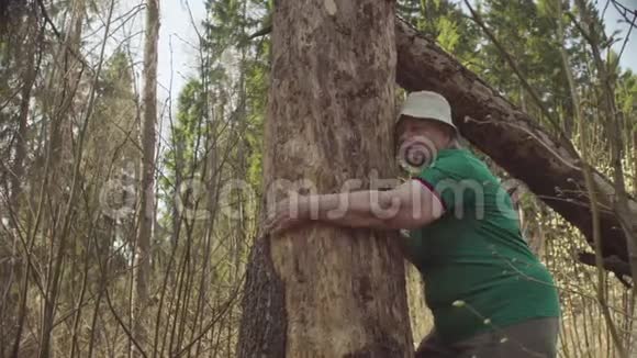 在森林里拥抱一棵损坏的树的老妇人视频的预览图