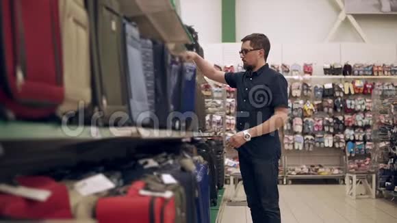 男购物者正从超市的货架上拿着塑料手提箱检查视频的预览图