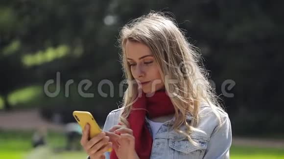 年轻美丽的女人在智能手机上使用应用程序的肖像在手机上微笑和发短信穿红色衣服的女人视频的预览图