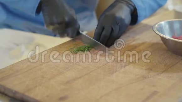 用黑色乳胶手套做饭在木切割板上切块视频的预览图