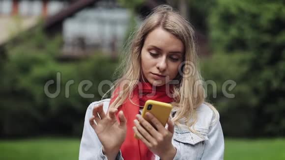 年轻美丽的女人在智能手机上使用应用程序的肖像在手机上微笑和发短信穿红色衣服的女人视频的预览图