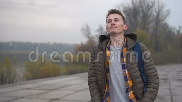 在多云城市行走的人英俊的白种人年轻男子穿着休闲夹克上路视频的预览图