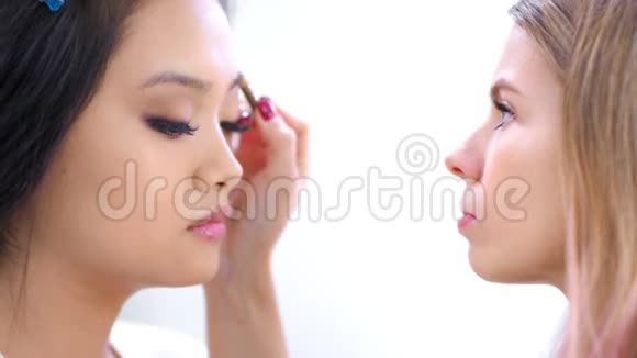 侧视专业化妆师为有吸引力的客户打造完美的眉毛造型视频的预览图