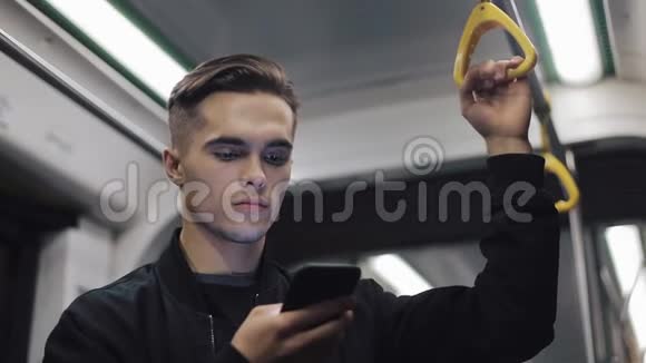 严肃男人的肖像在公共交通中握着扶手浏览智能手机视频的预览图