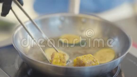 厨师炒菜在餐厅厨房特写厨师用手把玉米片放到煎锅上视频的预览图