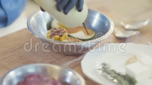 厨师手戴黑色乳胶手套腌制蔬菜玉米和碗里的西葫芦片视频的预览图