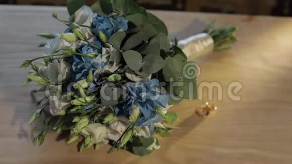 结婚戒指就在木制桌子上漂亮的结婚花束附近视频的预览图