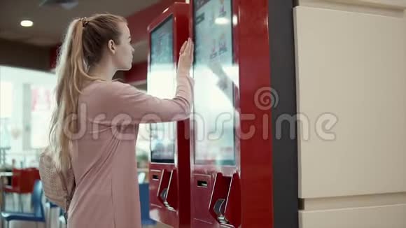 年轻的学生女孩正在大屏幕上选择快餐店的食物视频的预览图