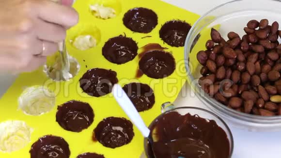 一个女人涂了一种硅胶模具用融化的白巧克力做糖果用刷子附近有杏仁视频的预览图