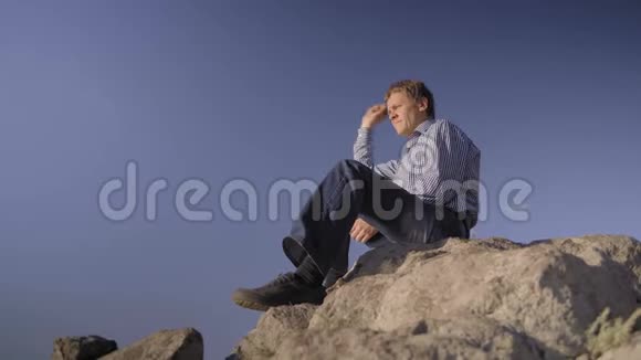 一个人坐在河岸上把石头扔进水里视频的预览图