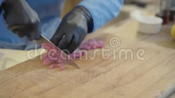 专业厨师双手戴黑色橡胶手套在餐厅厨房用锋利的大刀切肉视频的预览图