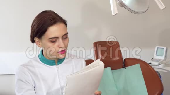 在她办公室工作的迷人的女牙医填写医疗文件视频的预览图