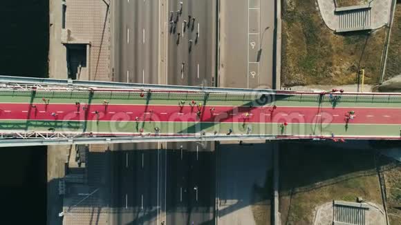 马拉松在人行天桥和道路上跑步俯视旋转镜头视频的预览图