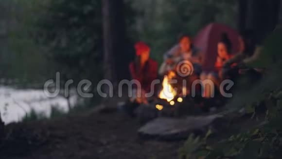旅行者浪漫的年轻人坐在森林篝火旁弹吉他唱歌的模糊镜头视频的预览图