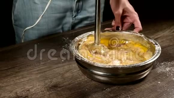 厨房里的一个糕点女孩在一个金属碗里用搅拌机打着面团做海绵蛋糕面粉鸡蛋和视频的预览图