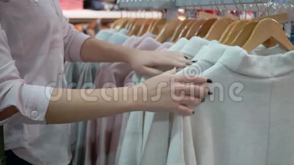 购物快乐的女孩年轻的顾客女性在购物中心的季节性折扣中选择时装店的新衣服视频的预览图
